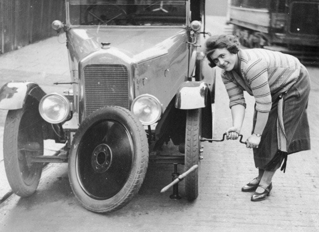 Detail of Ivy Cummings changing a tyre on a 1925 Singer 10/26, London, c1925 by Unknown