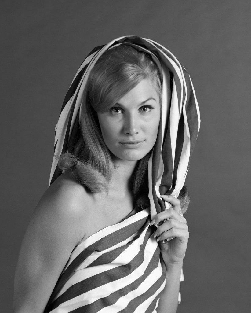 Detail of 1960s portrait woman wrapped in striped sheet with seductive expression on face looking at camera by Corbis