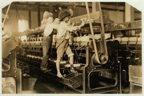Detail of Small boys climbing on spinning frame to mend broken threads and replace empty bobbins at Bibb Mill, Macon, Georgia, 1909 by Lewis Wickes Hine