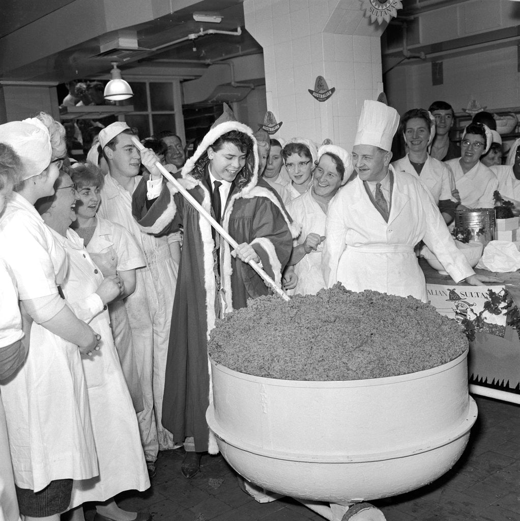 Detail of Cliff Richard mixing a giant Christmas pudding at J.Lyons in Cadby Hall, Hammersmith by Harry Hammond