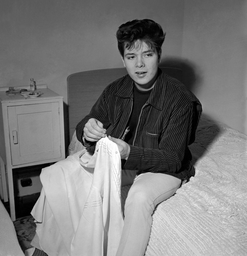 Detail of Cliff Richard in his first house sitting on a bed by Harry Hammond