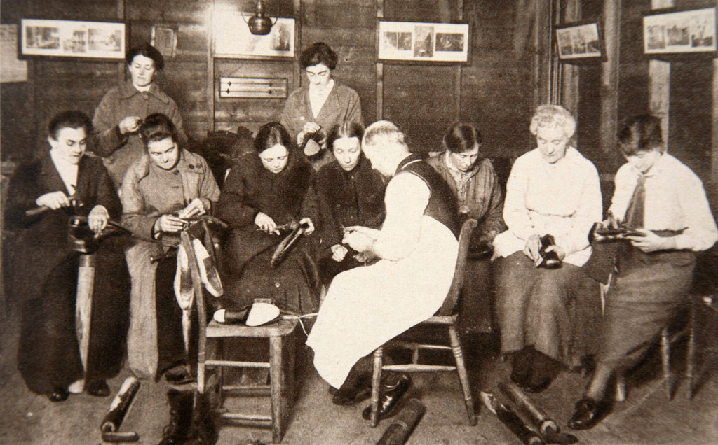 Detail of A group of women receive a lesson in boot repairing by S and G