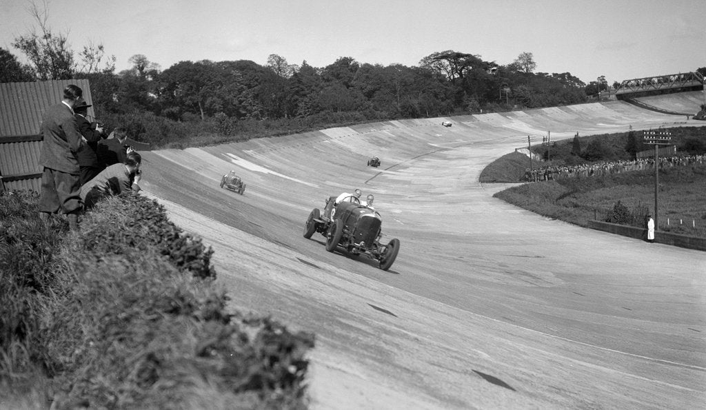 Detail of Eddie Hall's Bentley leading a Bugatti on the banking at Brooklands. by Bill Brunell