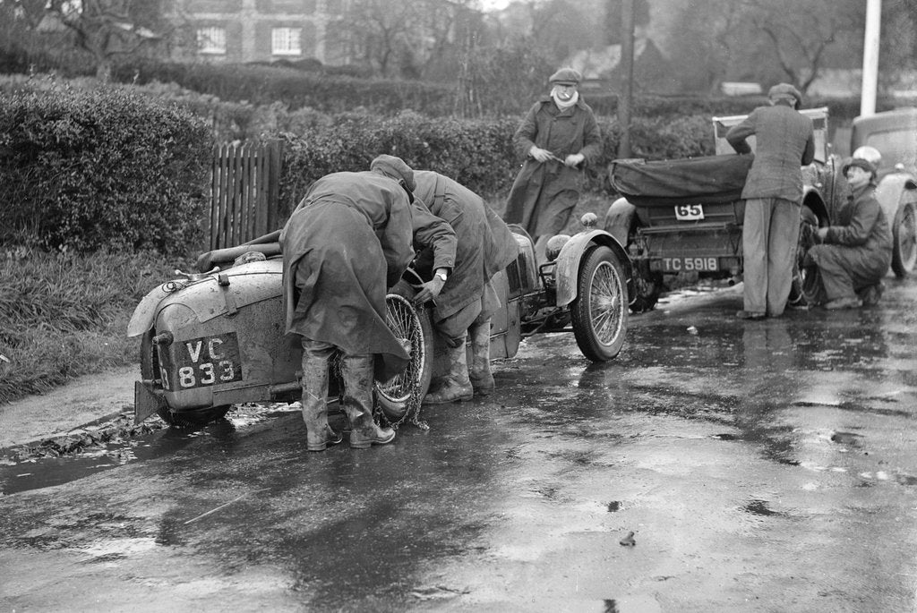 Detail of Attaching snow chains to JE Lancaster's Riley Brooklands during the Inter-Varsity Trial, 1930 by Bill Brunell