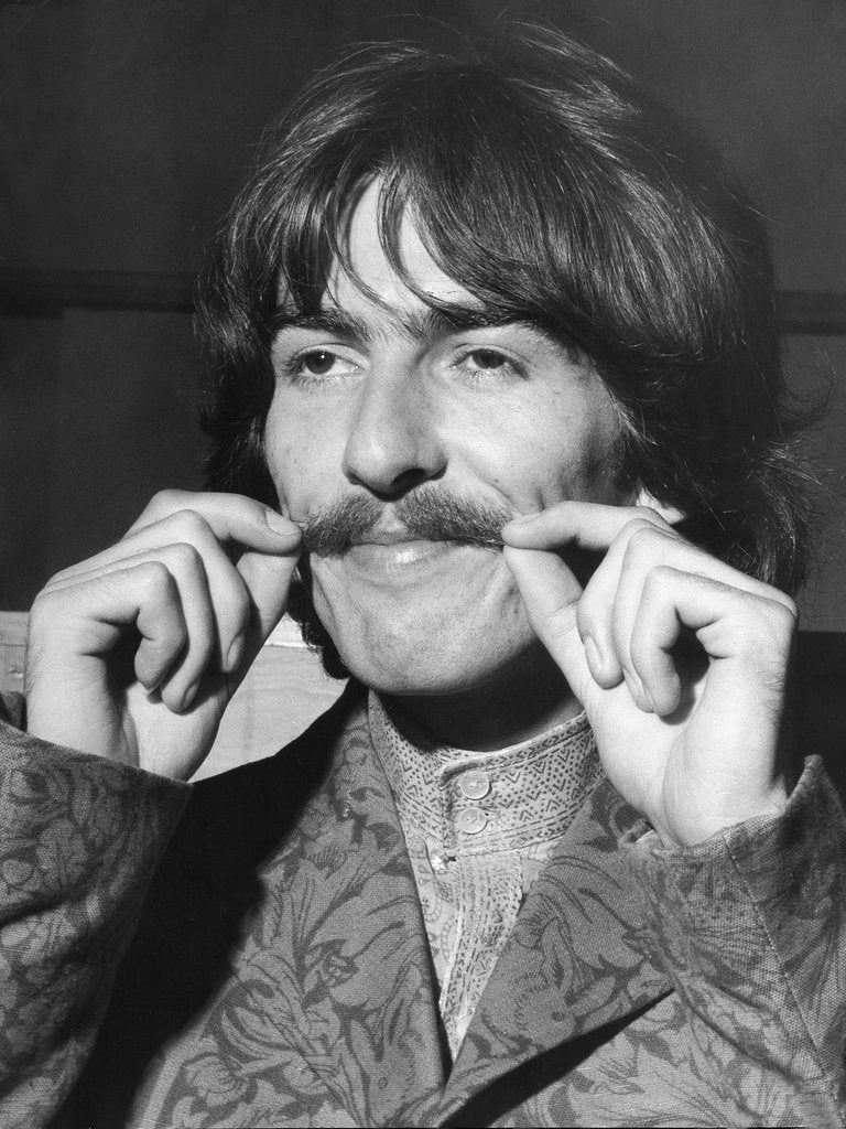 Detail of George Harrison plays with his moustache by Associated Newspapers