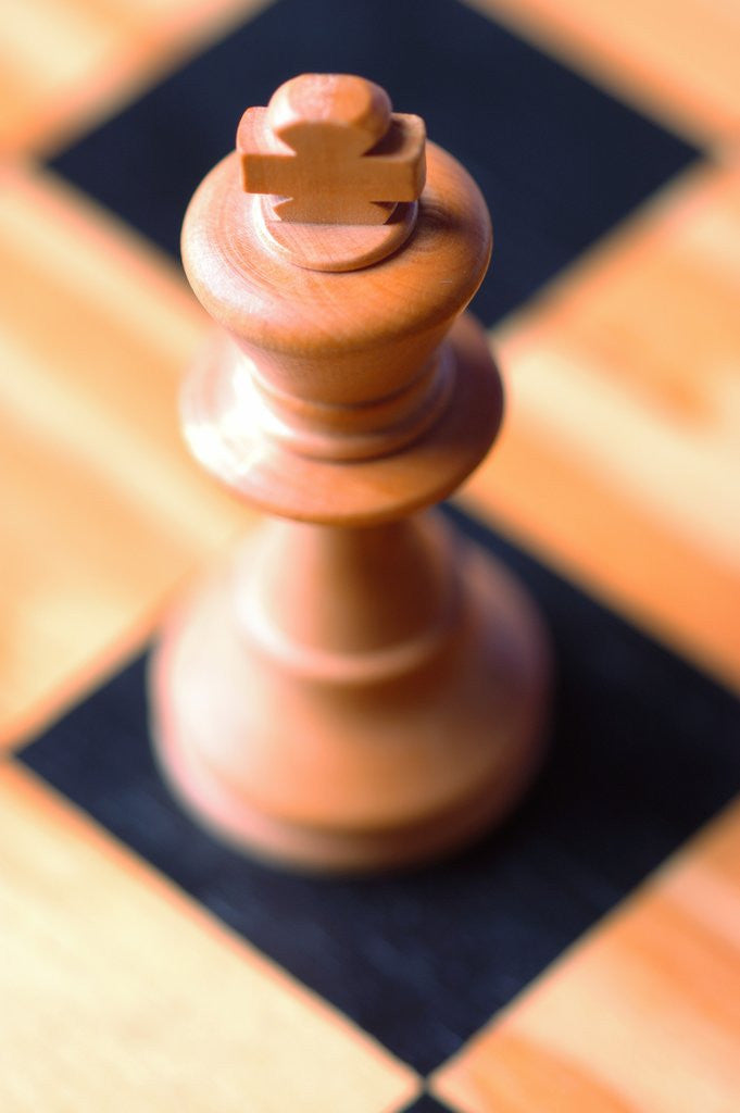 Detail of King chess piece on chessboard by Corbis