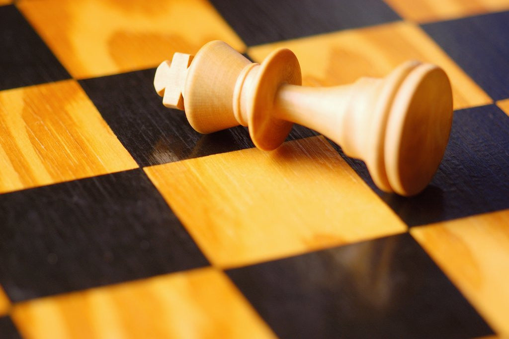 Detail of King chess piece lying on chessboard by Anonymous