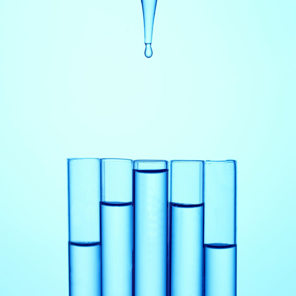 Detail of A glass pipette drops water in to a series of staggered test tubes or vials by Corbis