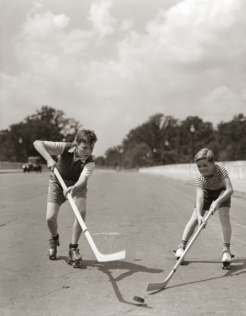 Detail of 1930s 1940s 2 Boys With Sticks And Puck Wearing Roller Skates Playing Street Hockey by Anonymous
