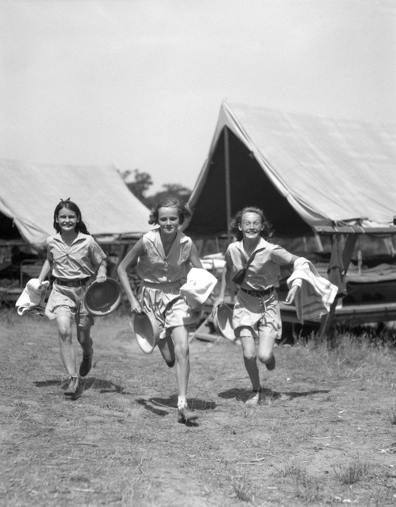 Detail of 1930s Three Teen Girls Wearing Camp Shorts and Shirts Running From Tents While Holding Towels and Wash Basins by Corbis