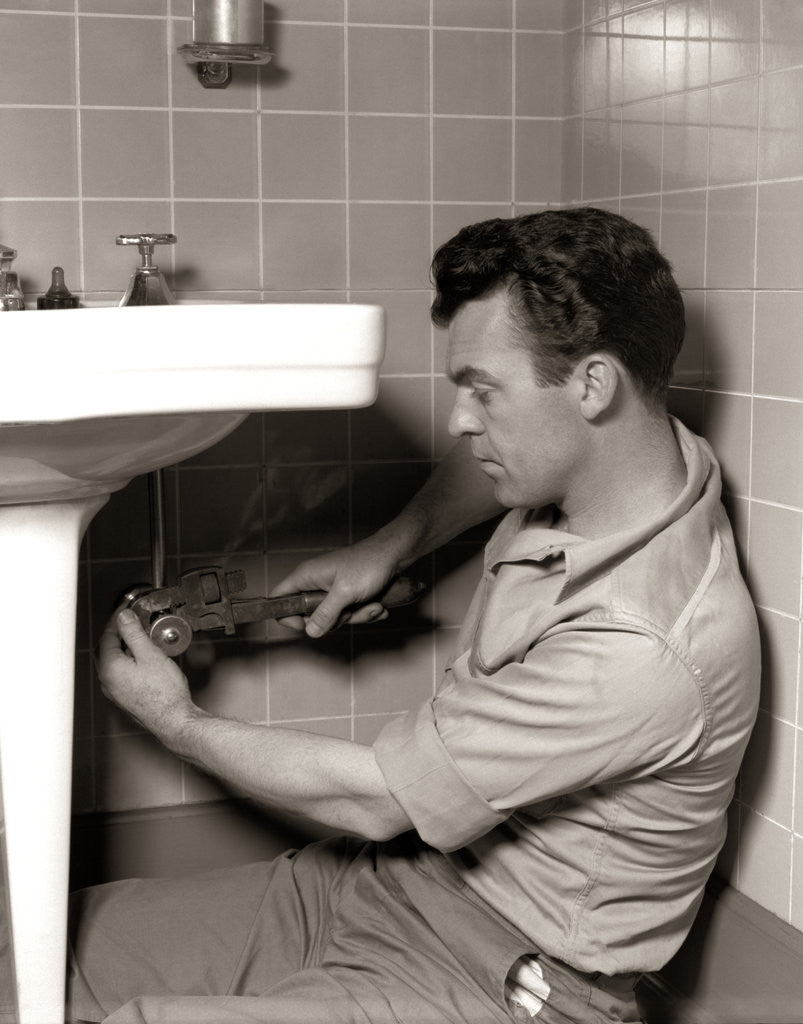 Detail of 1950s Man Plumber Fixing Bathroom Sink by Corbis