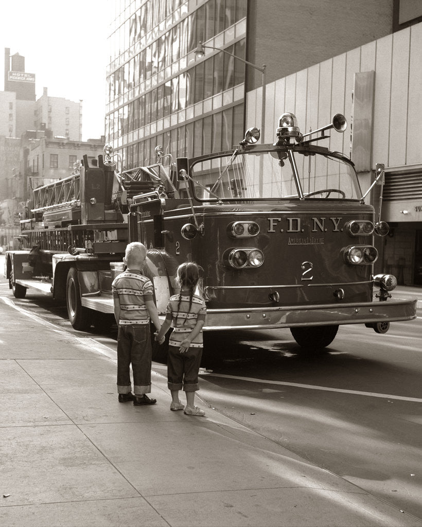 Detail of 1970s 2 Children Boy Girl Holding Hands Looking At Fire Truck Parked On Street New York City by Anonymous