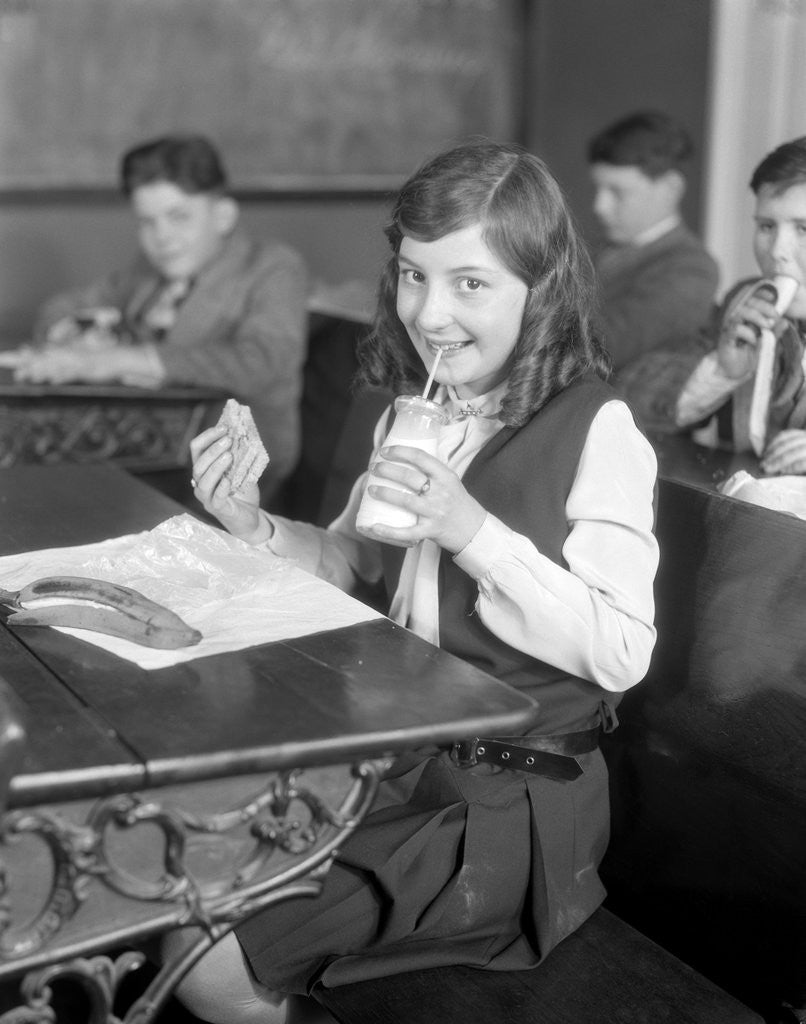 Detail of 1920s School Girl Eating Lunch At Her Desk Drinking From A Bottle Of Milk Holding A Sandwich by Anonymous