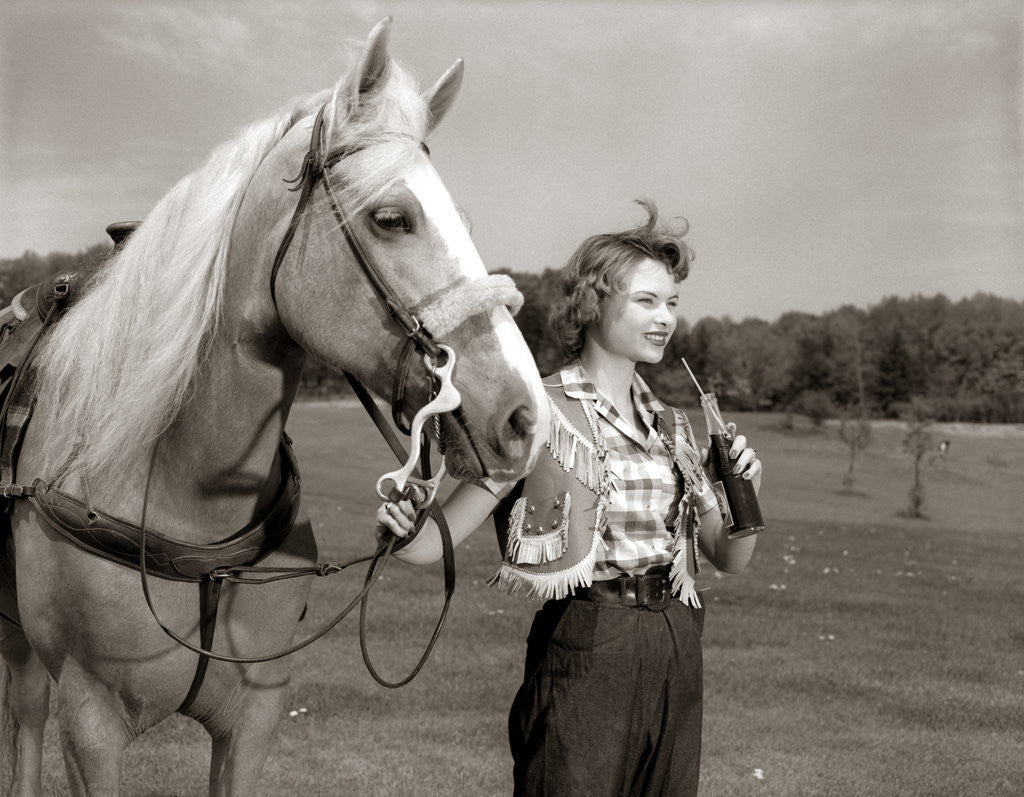 Detail of 1950s Teenage Girl Western Wear Holding Horse Halter Drinking Carbonated Beverage From Bottle by Anonymous