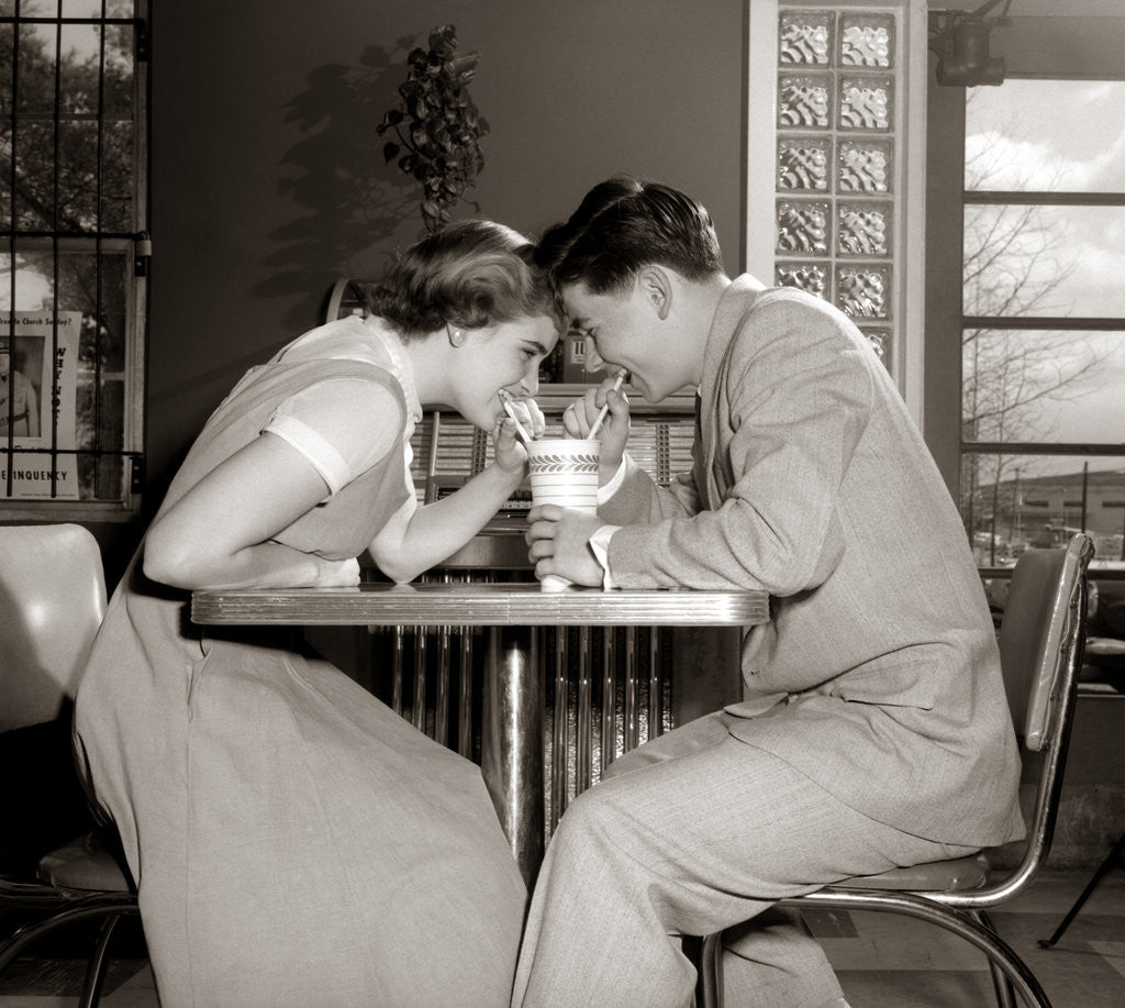 Detail of 1950s 1960s Laughing Teenage Boy and Girl Sharing Drink Together With Two Straws In Soda Shop by Anonymous