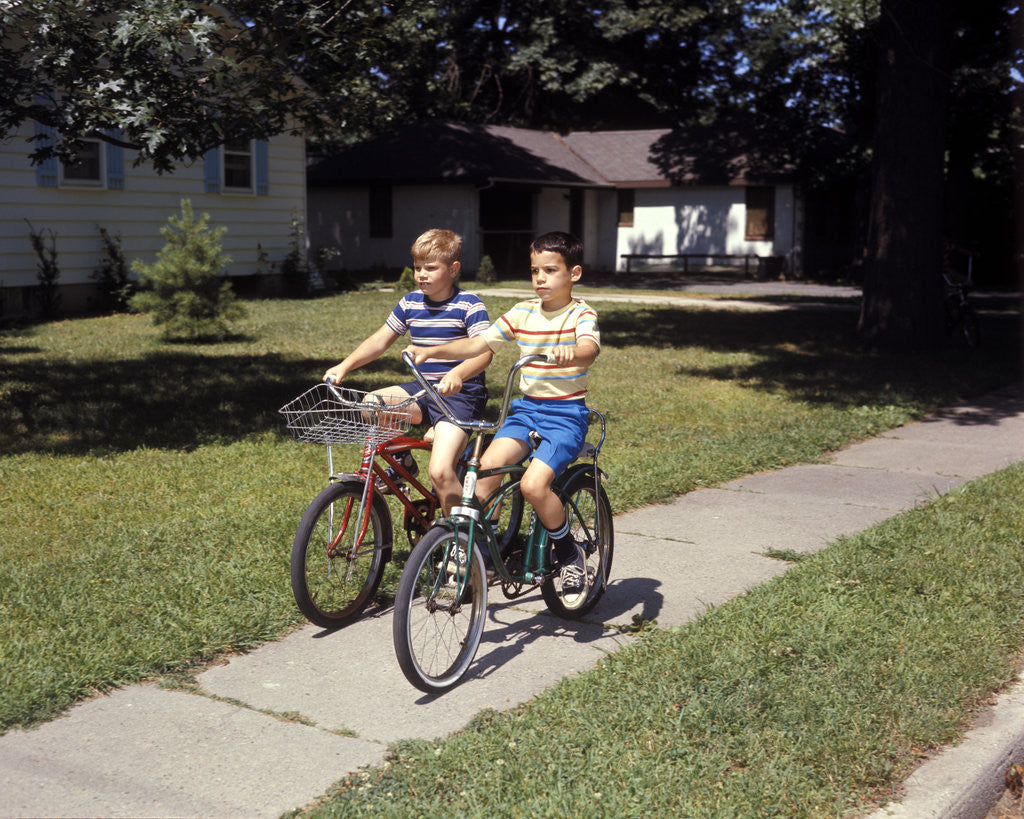 Detail of 1970s Two Boys Riding Bikes Down Suburban Neighborhood Sidewalk by Corbis