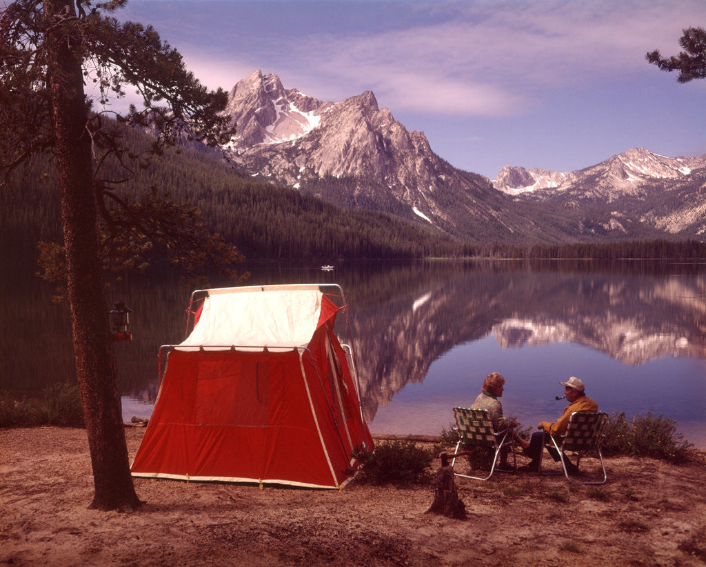Detail of 1970s Elderly Couple Camping Sitting By Red Tent Stanley Lake Idaho by Anonymous