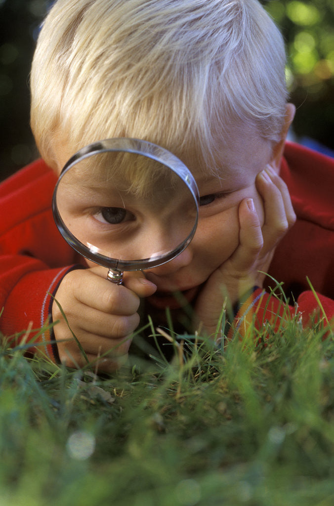 Detail of 1980s Boy Using Magnifying Glass by Corbis