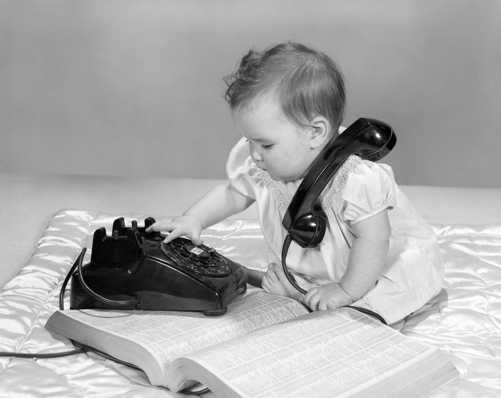 Detail of 1950s 1960s Baby Girl With Telephone Book Dialing Phone by Anonymous