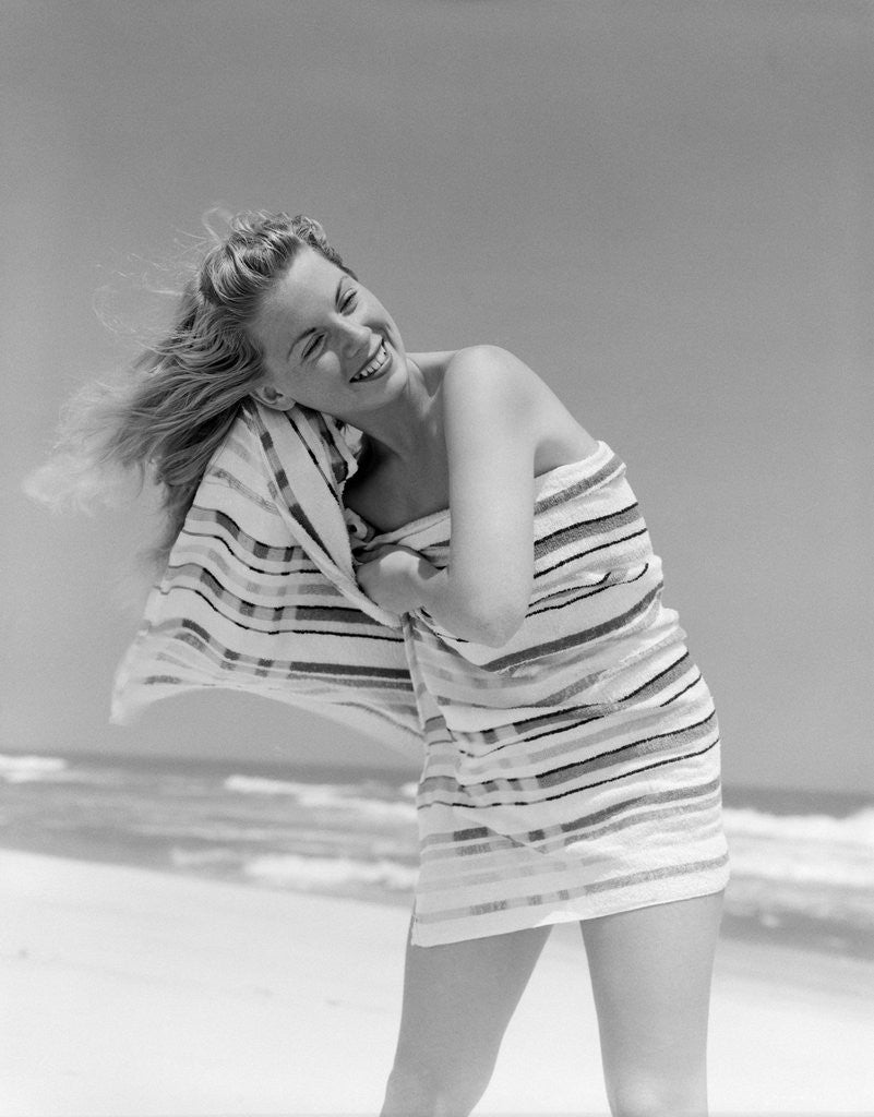 Detail of 1950s 1960s Woman Wrapped In Stripped Towel Drying Hair On Beach Smiling by Anonymous