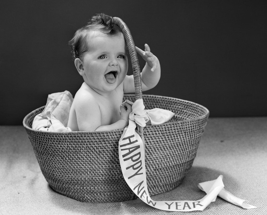 Detail of 1940s Baby Sitting In Wicker Basket With Happy New Year Banner Studio Indoor by Anonymous