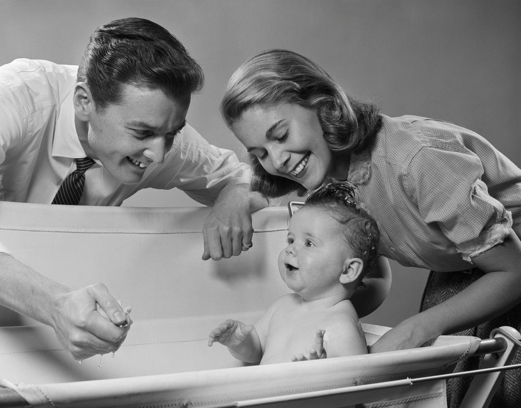 Detail of 1950s Parents Leaning Over Tub Bathing Happy Baby by Corbis