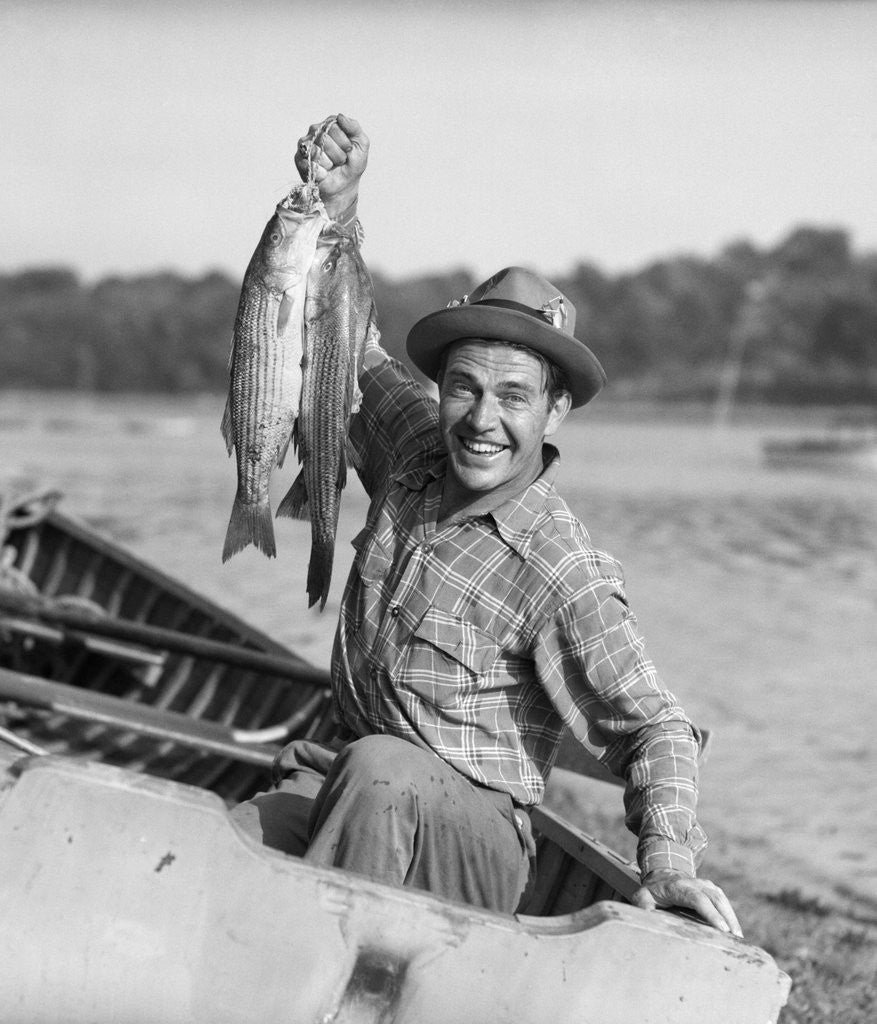 Detail of 1940s 1950s Happy Man Fishing From A Rowboat Holding Up Fish Just Caught With Pride by Corbis