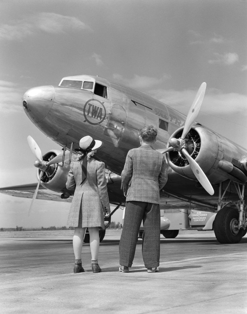 Detail of 1940s Rear View Of Boy and Girl Standing Together Looking At Propeller Airplane Outdoor by Anonymous