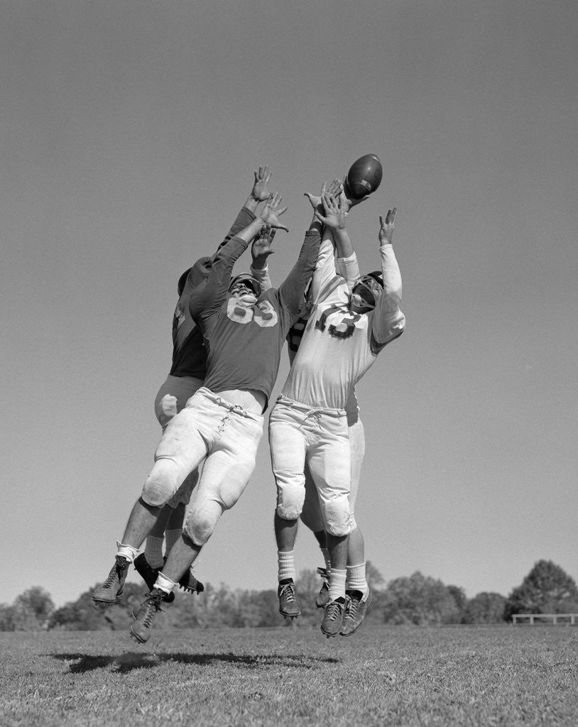 Detail of 1960s Three Football Players Reaching To Catch Ball by Corbis