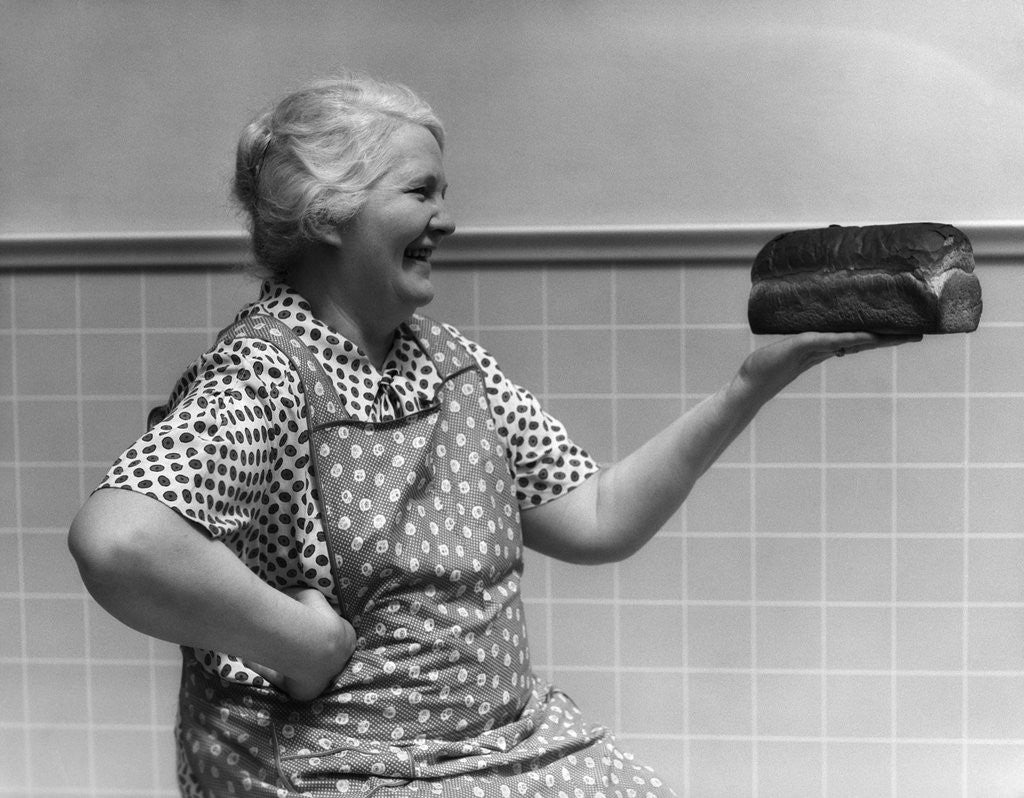 Detail of 1930s 1940s Grandmother In Apron Admiring Loaf Of Freshly Baked Bread by Corbis