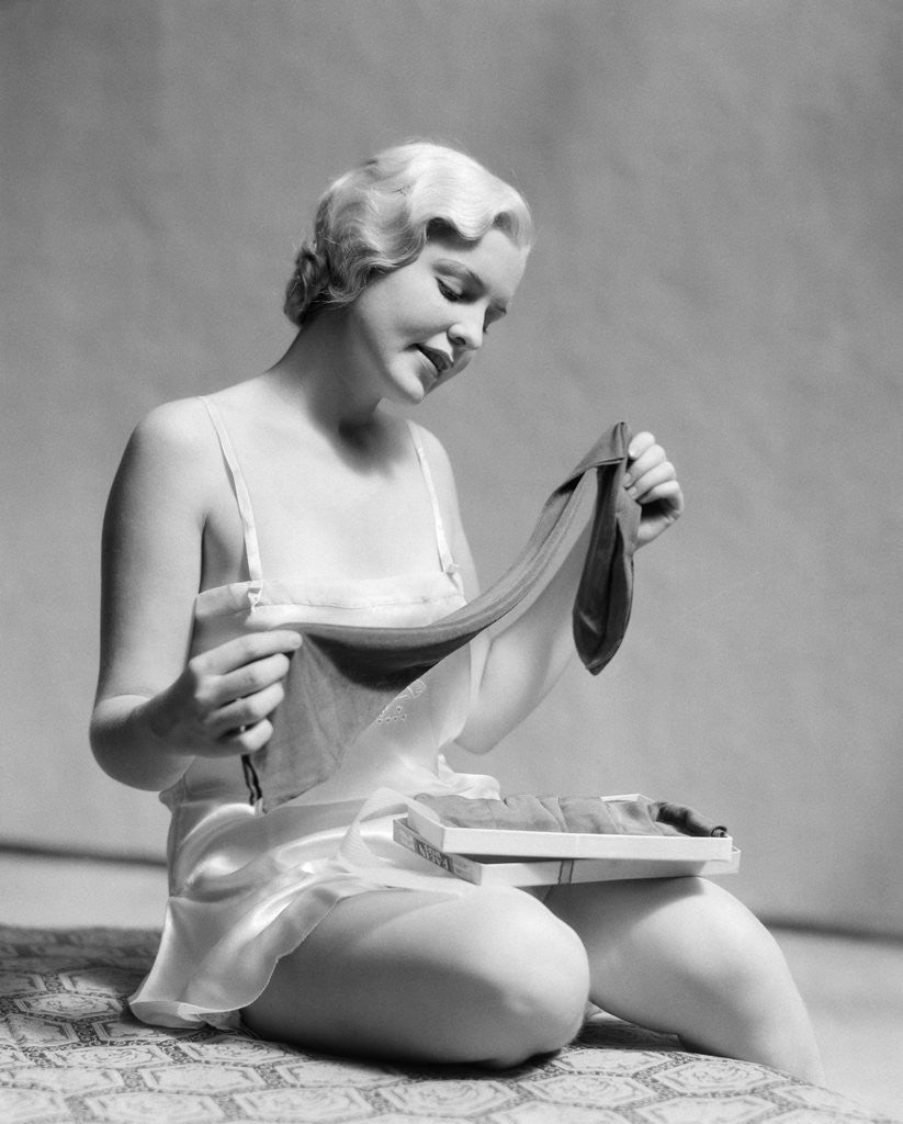 Detail of 1930s Woman In Silk Teddy Lingerie Opening A Box Of Hosiery by Anonymous