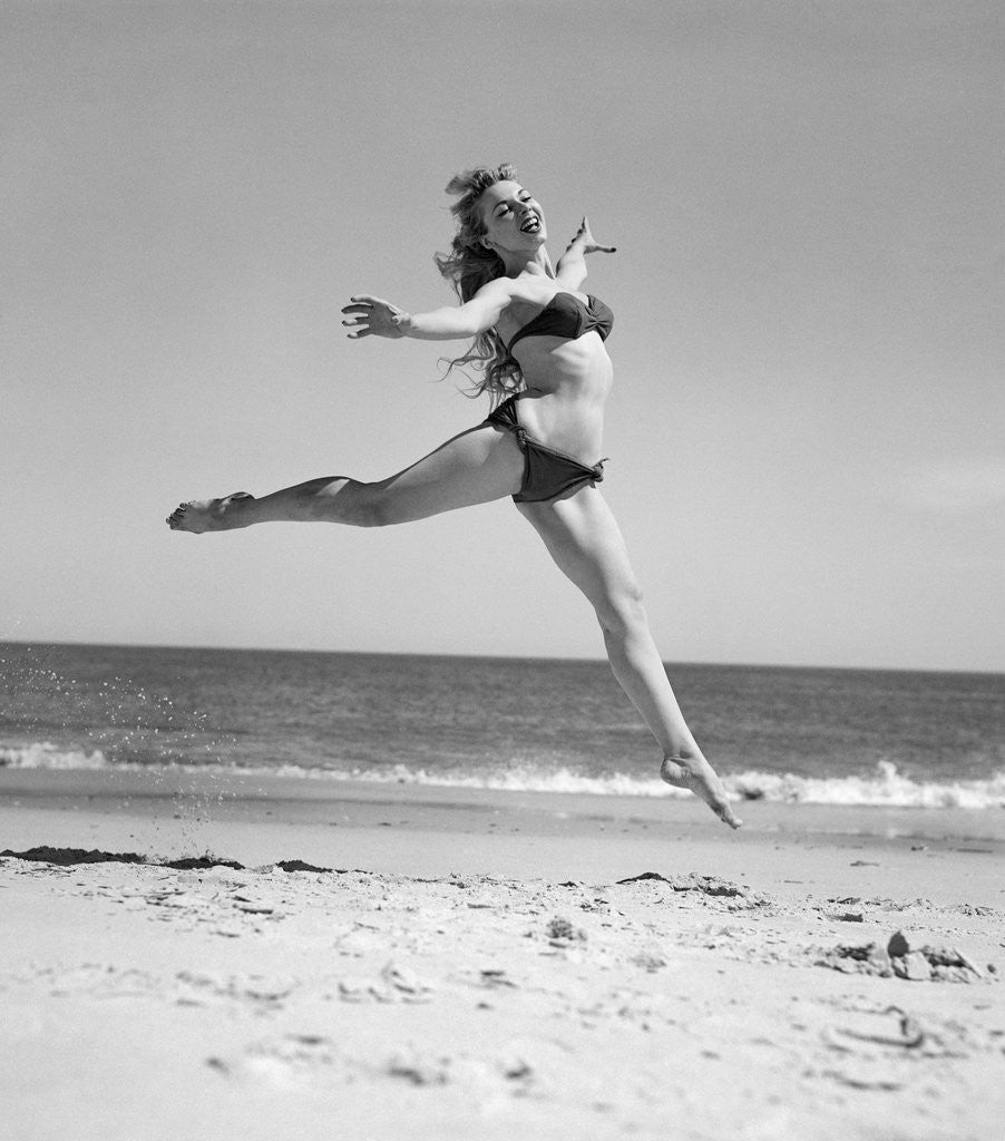 Detail of 1950s Woman In Bikini Running And Jumping On The Beach Smiling by Corbis