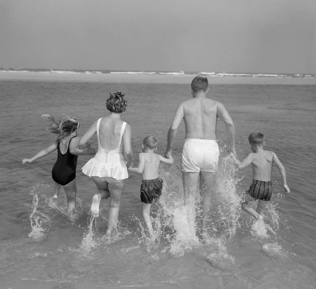 1960s Back View Of Family Of 5 Holding Hands Running Into Ocean by Corbis