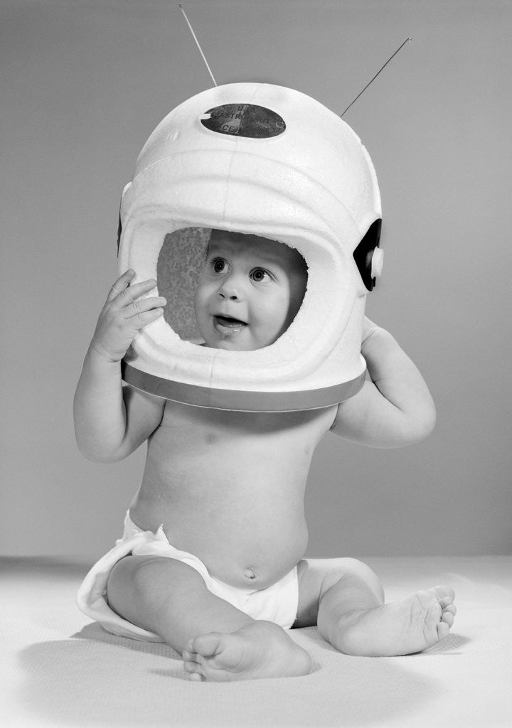 Detail of 1960s Baby In Diaper Seated Holding Astronaut Helmet With Antennae On Head by Anonymous