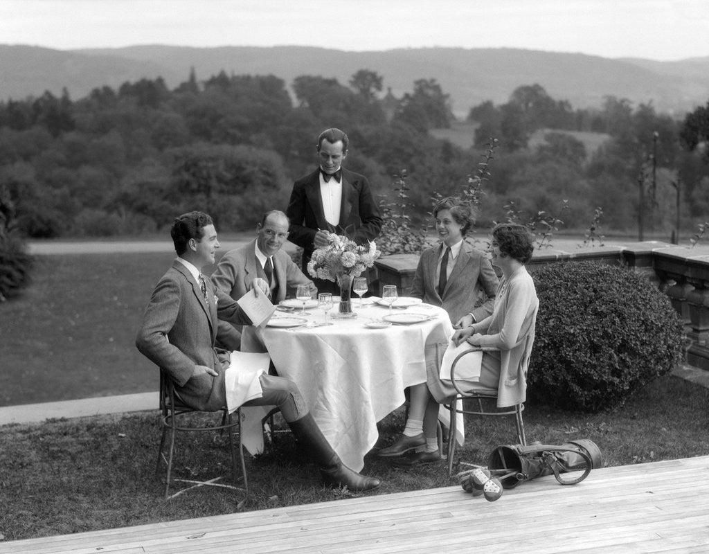 Detail of 1920s 1930s Country Club Scene With Two Couples With Golf Clubs Having Lunch Outdoors by Corbis