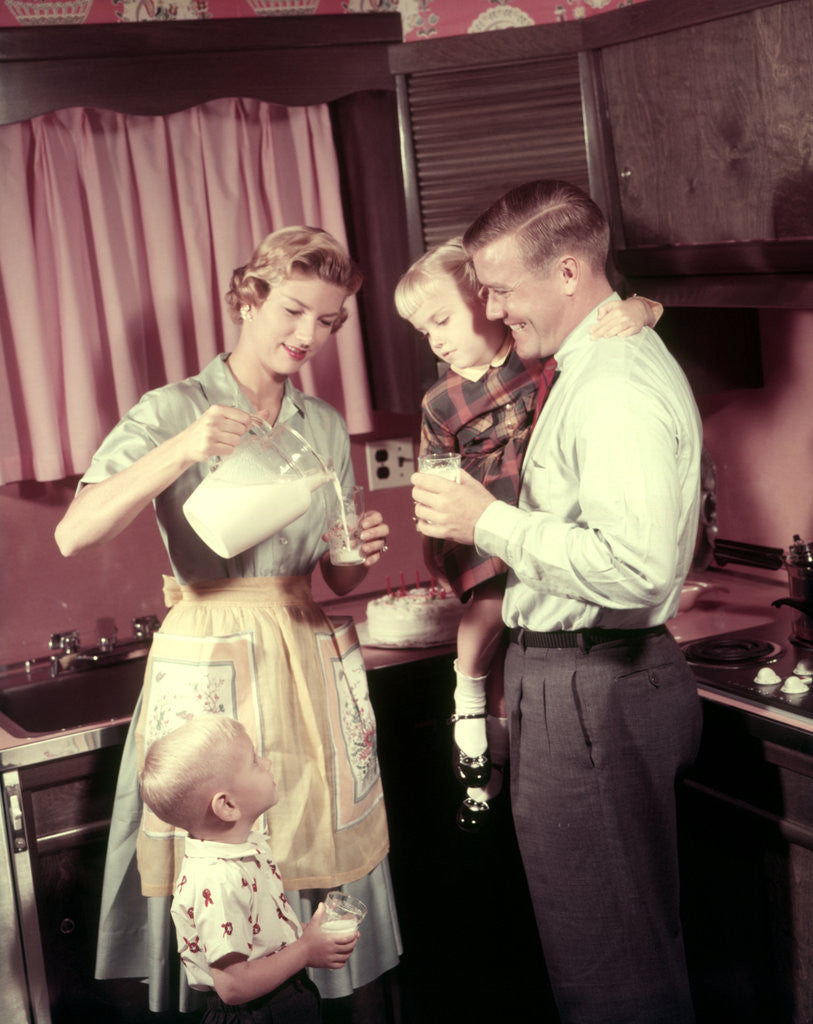 Detail of 1950s Family In Kitchen Mother Pouring Milk From Pitcher For Dad And Kids by Anonymous