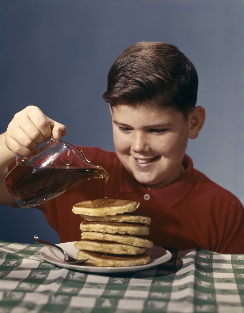 Detail of 1950s 1960s Boy Pouring Syrup On Breakfast Pancakes by Corbis