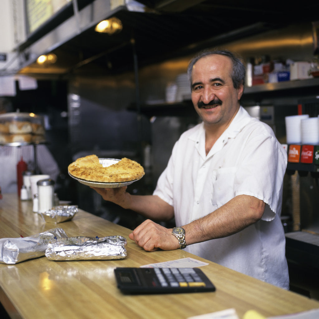 Detail of Portrait Man Working Behind Counter In Diner Holding Pie by Corbis