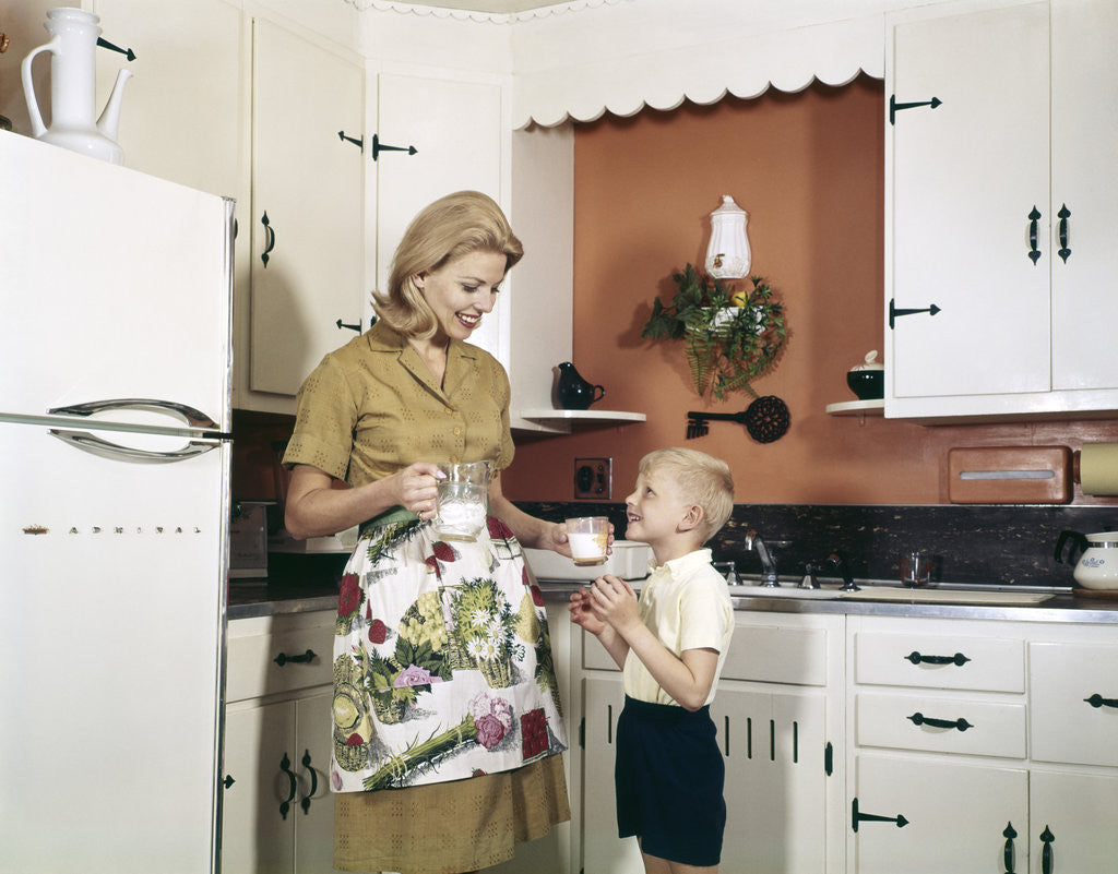 Detail of 1970s Mother Handing Glass Of Milk To Son In Kitchen by Anonymous