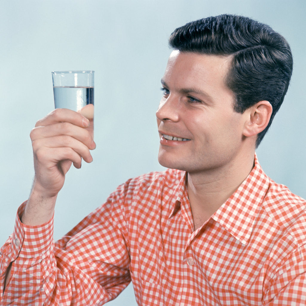 Detail of 1960s Profile Man Wearing Red Checkered Shirt Holding Glass Of Water by Corbis