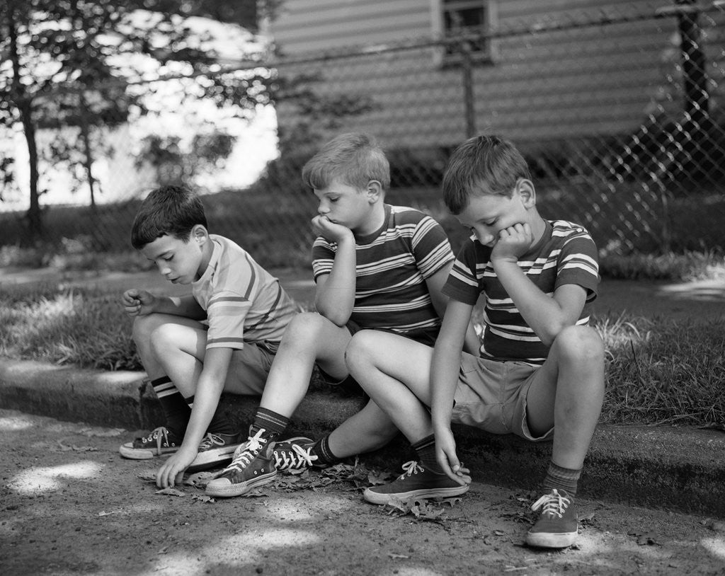 Detail of 1970s Three Bored Boys Sitting On Curb All Wearing Striped Tee Shirts Shorts And Sneakers by Anonymous