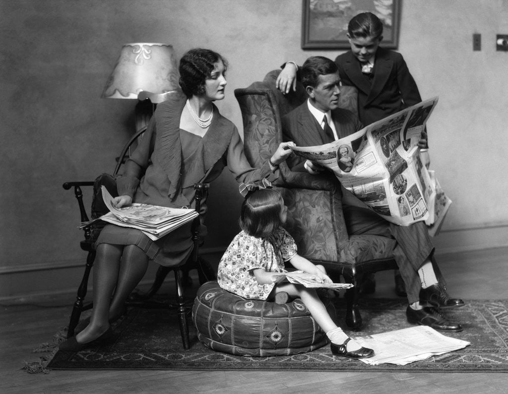 Detail of 1920s Family of Four Mother Father Son Daughter in Living Room Reading Newspaper Together by Corbis