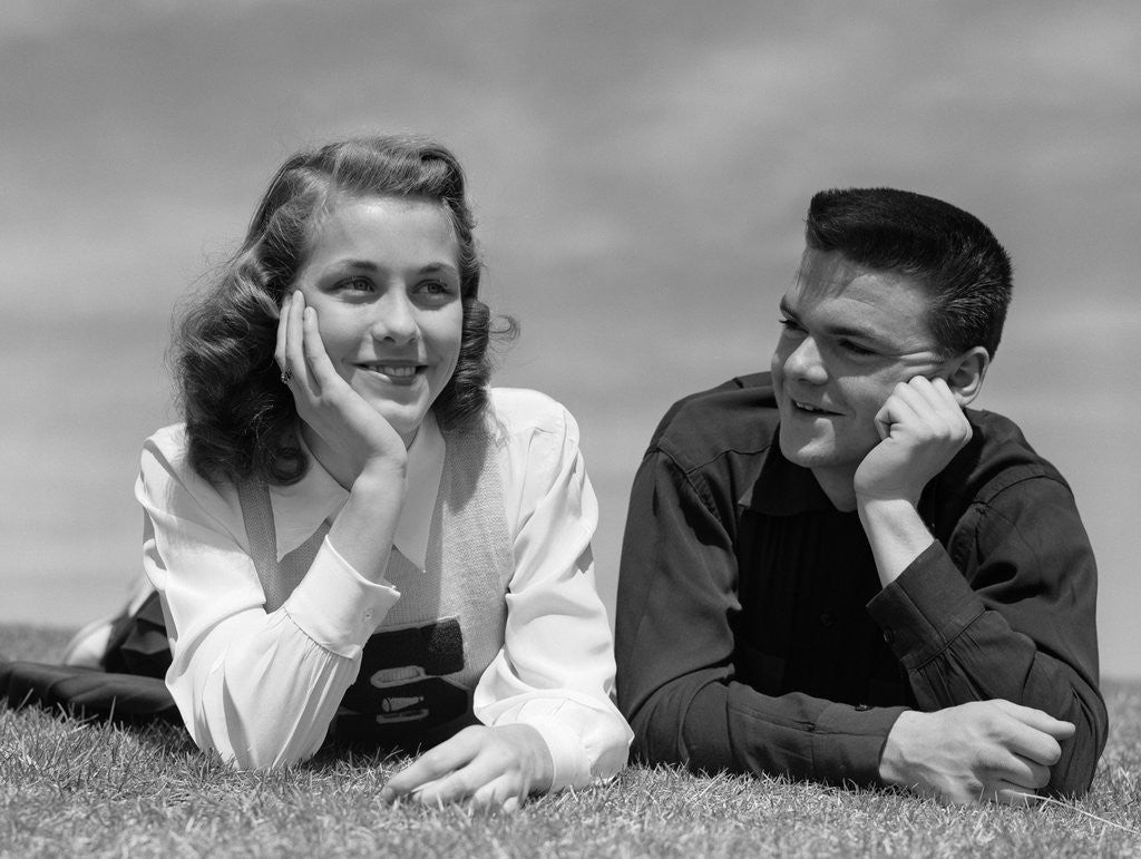 Detail of 1950s Teenage Couple Laying On Grass, Boy Gazing At Girl Wearing Cheerleader Sweater by Anonymous