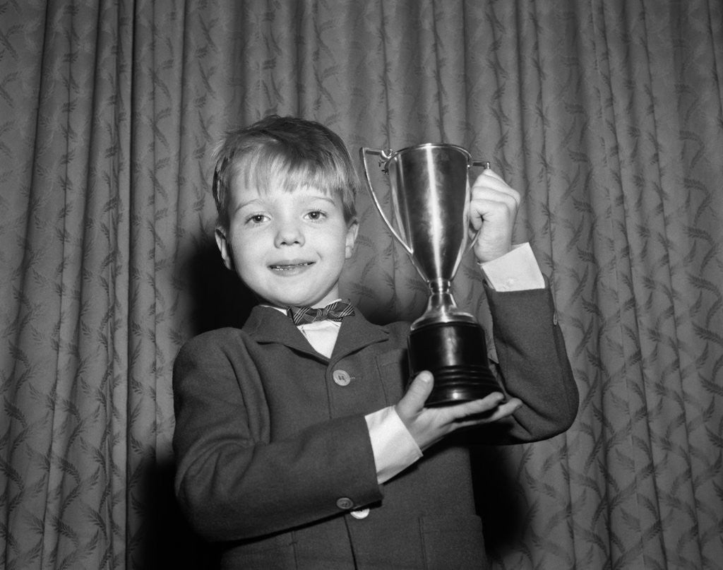 Detail of 1950s Proud Boy Holding Up Trophy Award by Corbis