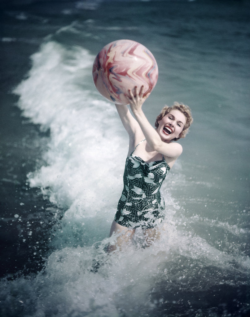 Detail of 1950s Woman Jumping In Surf Holding Up Beach Ball by Anonymous