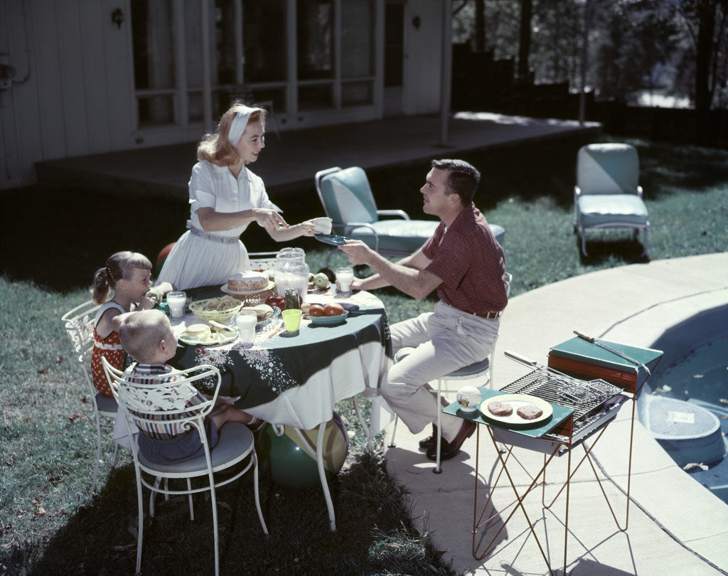 Detail of 1950s Family In Backyard Having Picnic From Grill Near Swimming Pool by Anonymous