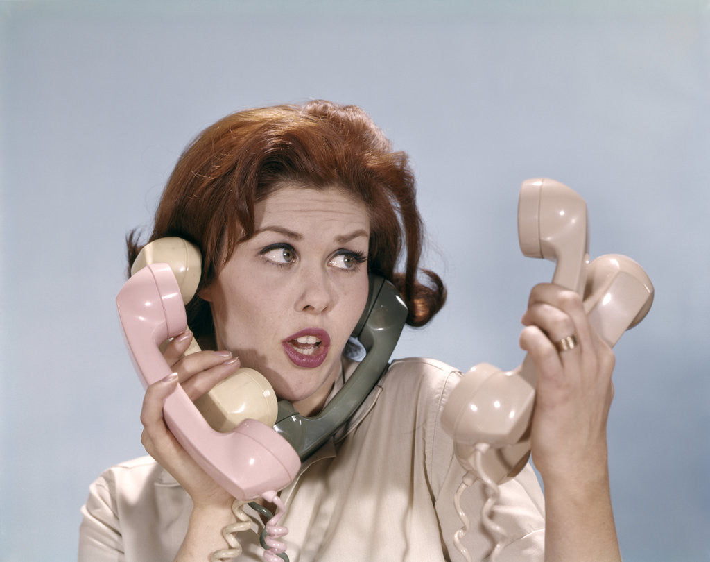 Detail of 1960s Frustrated Young Redheaded Woman Trying To Answer Handle Five Telephone Receivers Studio by Anonymous
