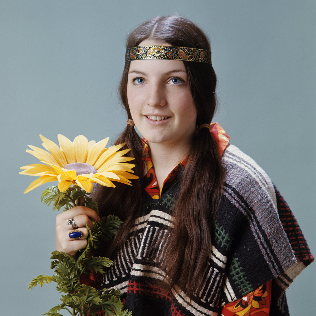 Detail of 1960s 1970s Teenage Girl With Pigtails Wearing Headband And Serape Holding Sunflower by Anonymous