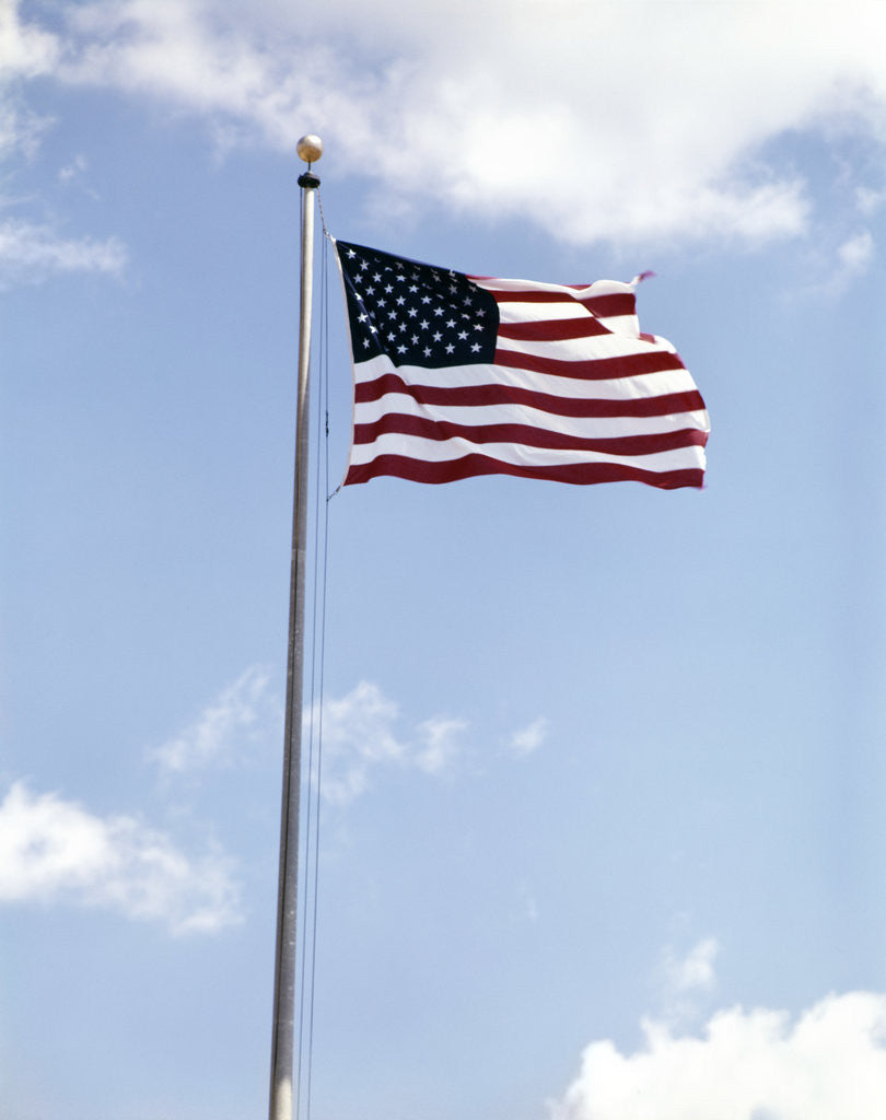 Detail of 1960s American Flag On Pole Flying Against Blue Sky With Clouds by Anonymous