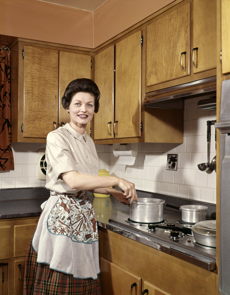 Detail of 1960s Woman Housewife Wearing An Apron Stirring Cooking Pot At Kitchen Stove by Corbis
